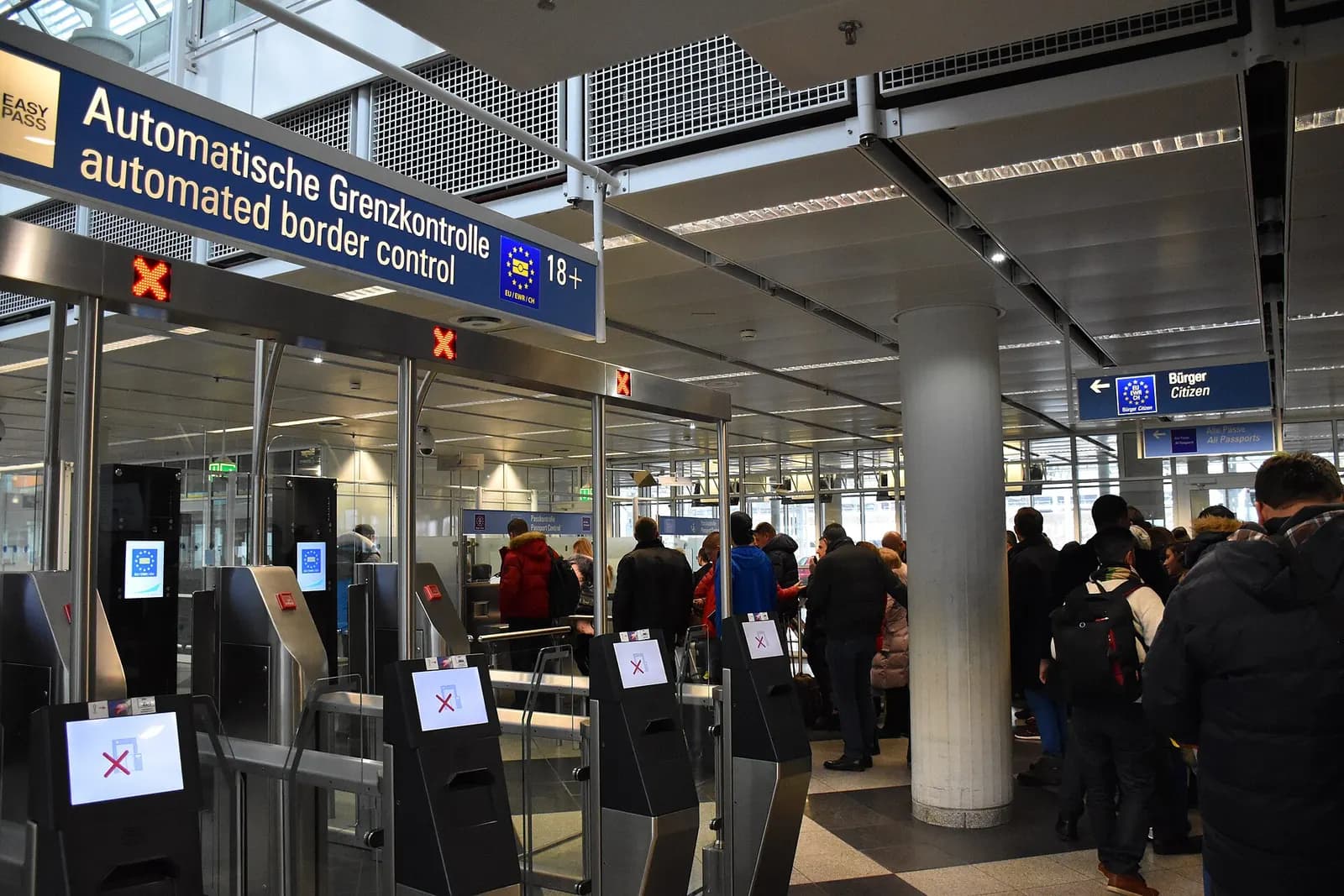Passport control booths and queue lanes in Terminal 1 Module B, with signage directing passengers through border inspection.