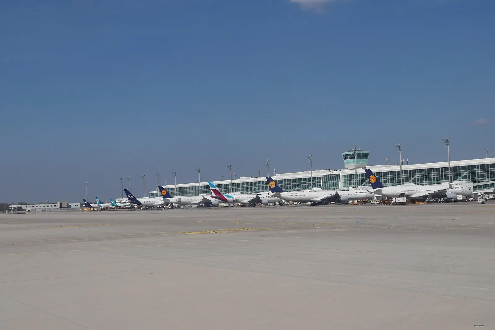 The modern glass-and-steel Terminal 2 Satellite building stands on the apron, connected to the main terminal by an underground walkway.