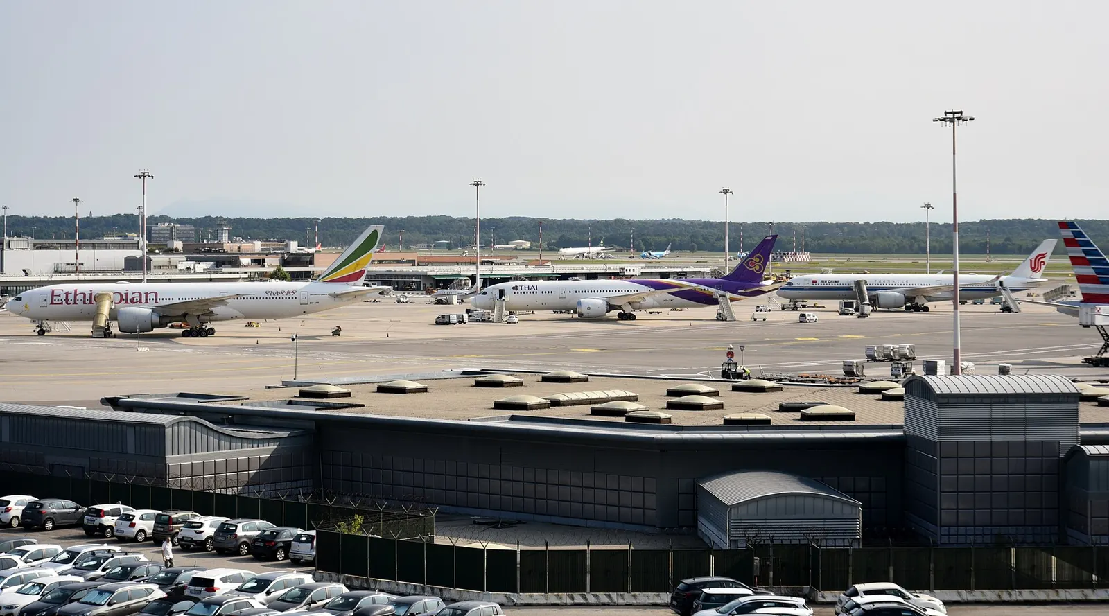 Three wide-body jets from Ethiopian Airlines, Thai Airways, and Air China parked in a row along Terminal 1.