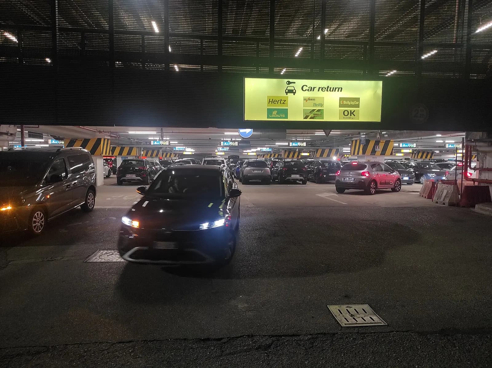 Ground-level entrance at Terminal 1 with signs for rental cars, parking, and passenger pickup areas.