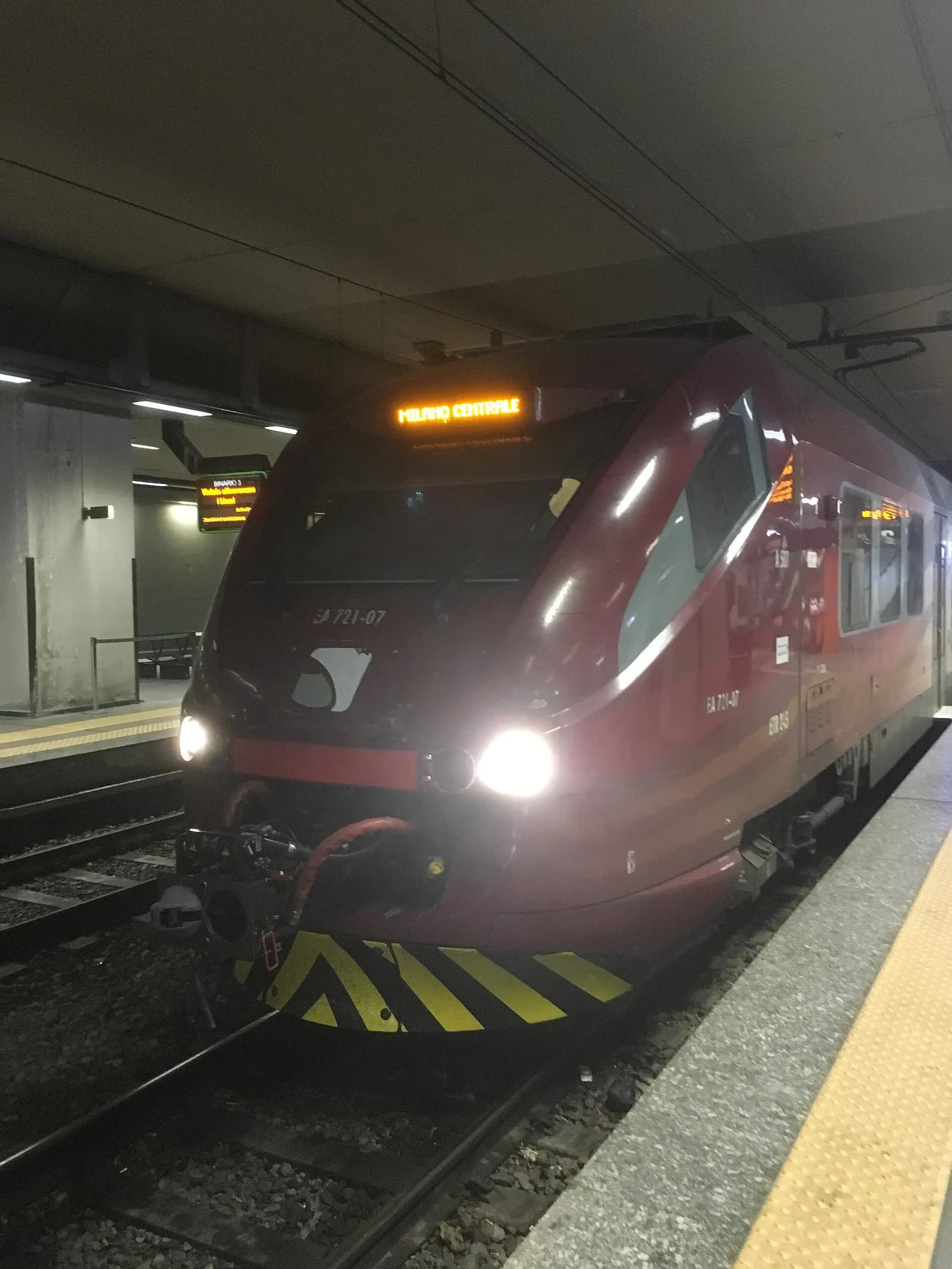 A Malpensa Express train waiting at the Malpensa Aeroporto station platform under a covered concourse.