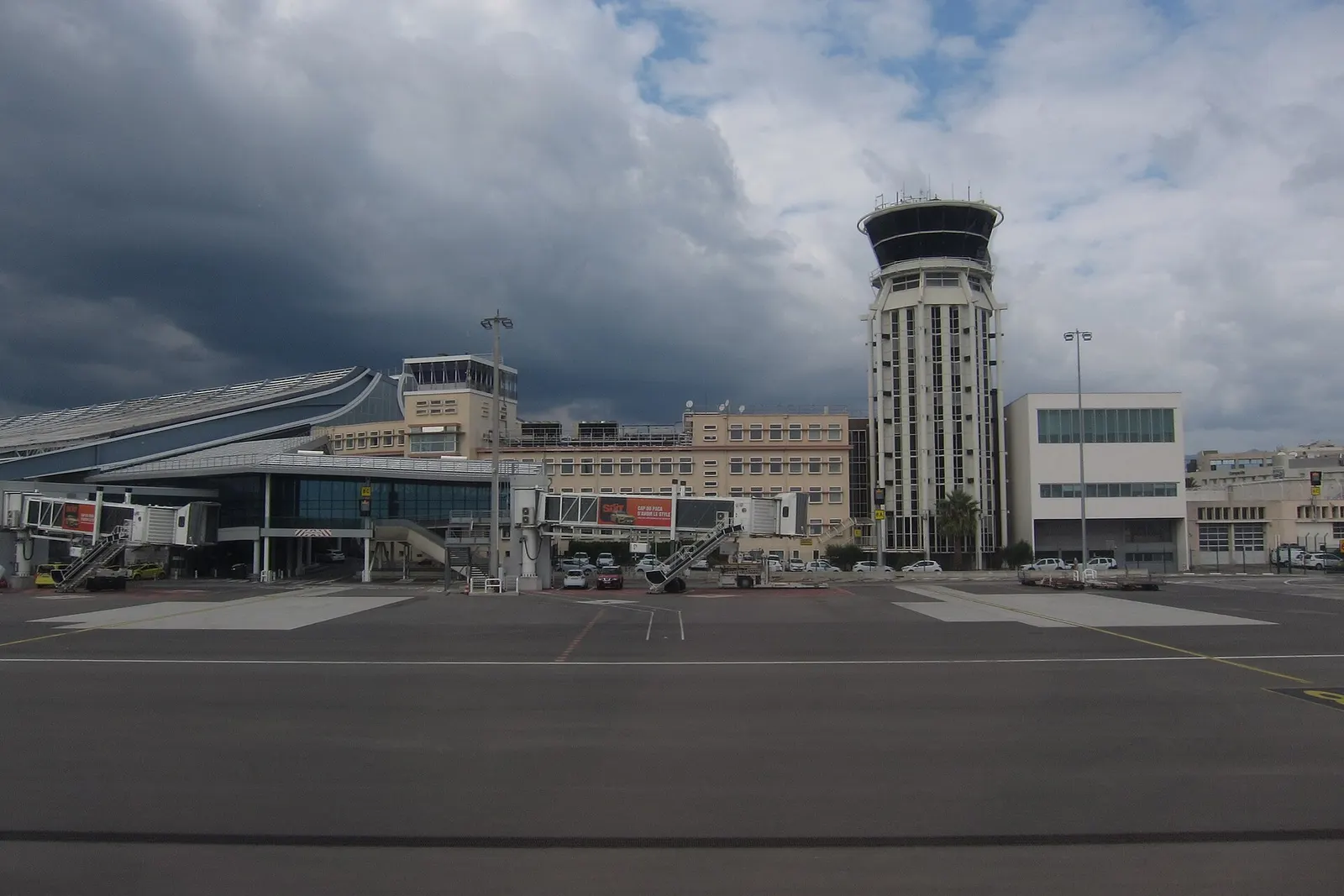 The Nice airport control tower and the modern eastern extension of Terminal 1 under a clear sky in October 2021.