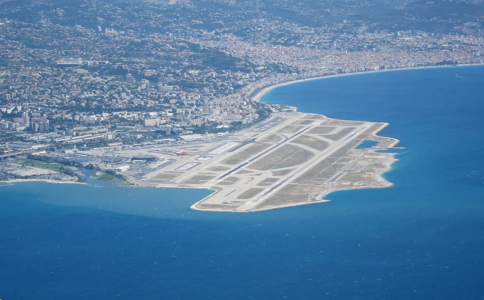 Aerial view of Nice Côte d'Azur Airport on the Mediterranean coast, with the Var river mouth at left and the city of Nice in the background.