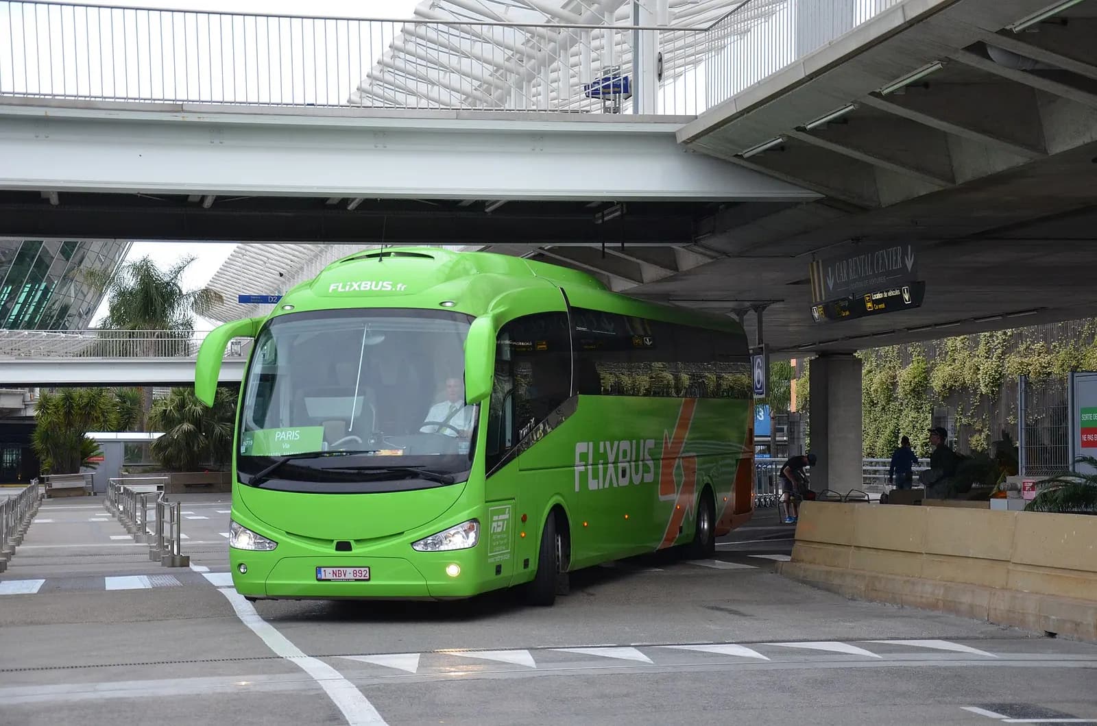 A white FlixBus coach parked at Nice Côte d'Azur Airport, showing long-distance bus service at the terminal curb.