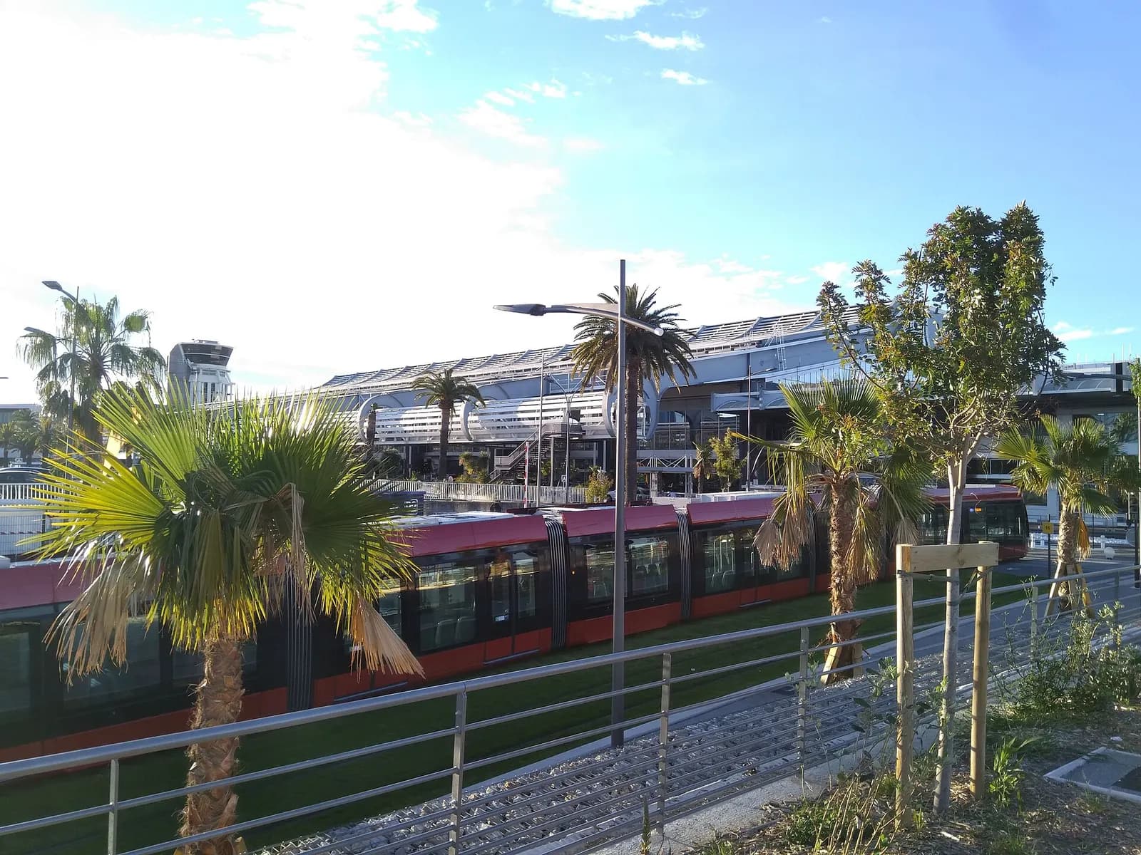 Terminal 1 at Nice Côte d'Azur Airport with the airport tram stop and tracks in the foreground connecting the terminal to central Nice.