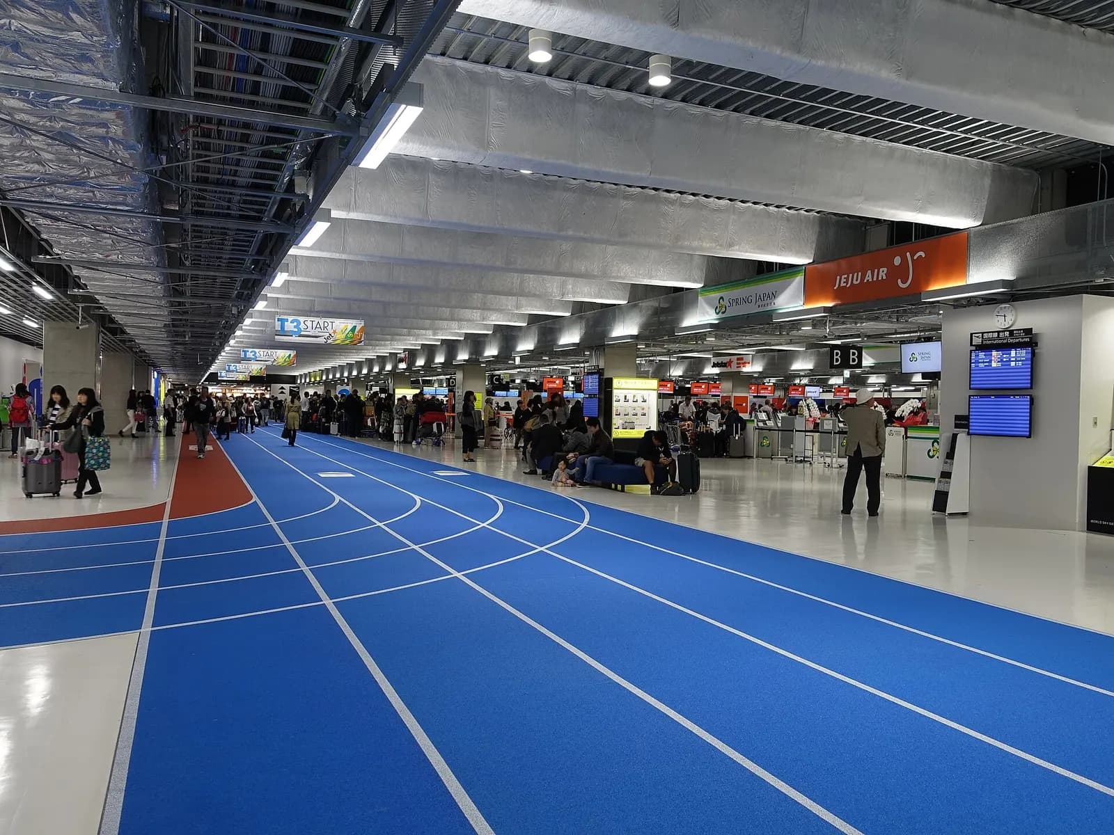 The open second-floor departure lobby of Terminal 3 with check-in counters, bright lighting, and a compact low-cost-carrier layout.