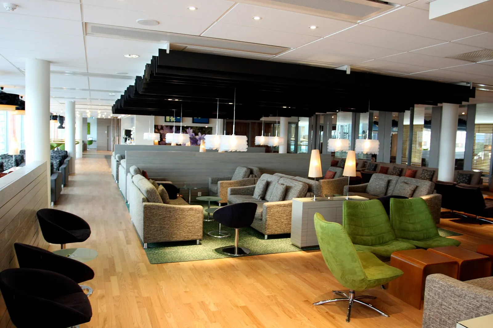 Interior of the Oslo Lounge at Gardermoen Airport with modern armchairs, tables, and soft lighting in a quiet seating area.