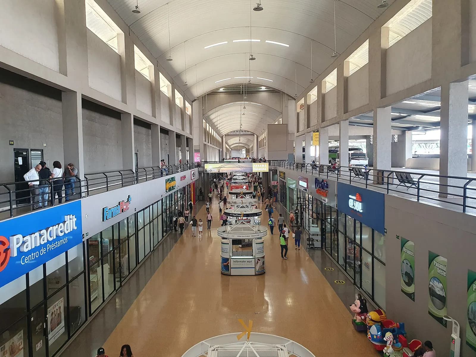 Bright multi-level interior hall of the Albrook Bus Terminal with travelers and waiting areas.