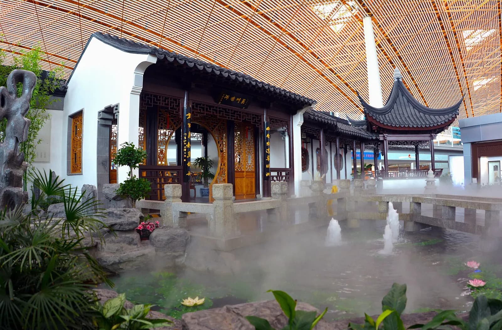 Indoor waterfall cascading over rocky landscaping inside Terminal 3 beneath exposed wooden ceiling beams.