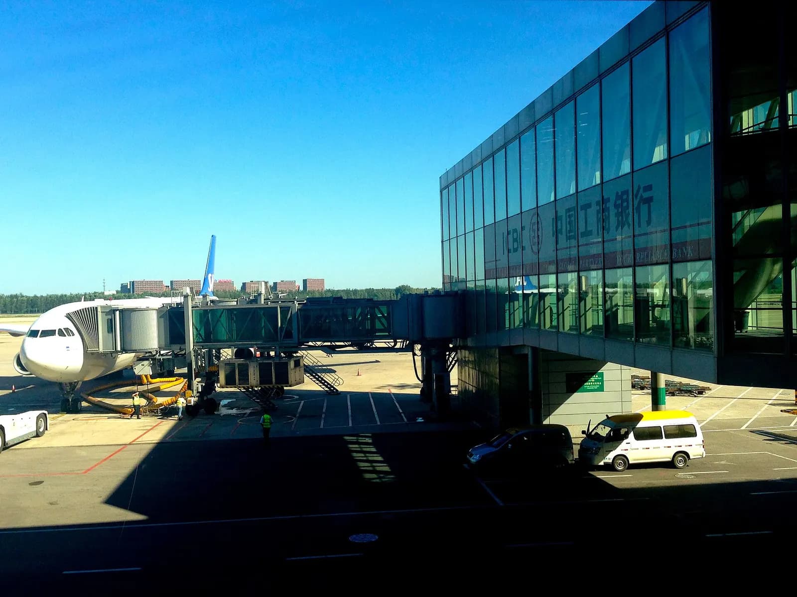 Glass-walled passenger boarding bridge at Terminal 3 connecting the gate lounge to an aircraft on the apron.