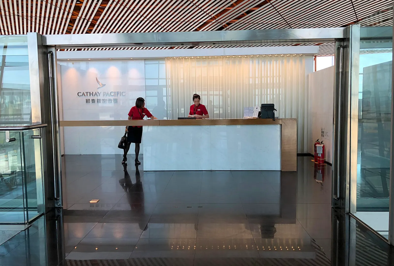 Interior of the Cathay Pacific lounge at Terminal 3E with seating areas, buffet counters, and large windows near the gates.