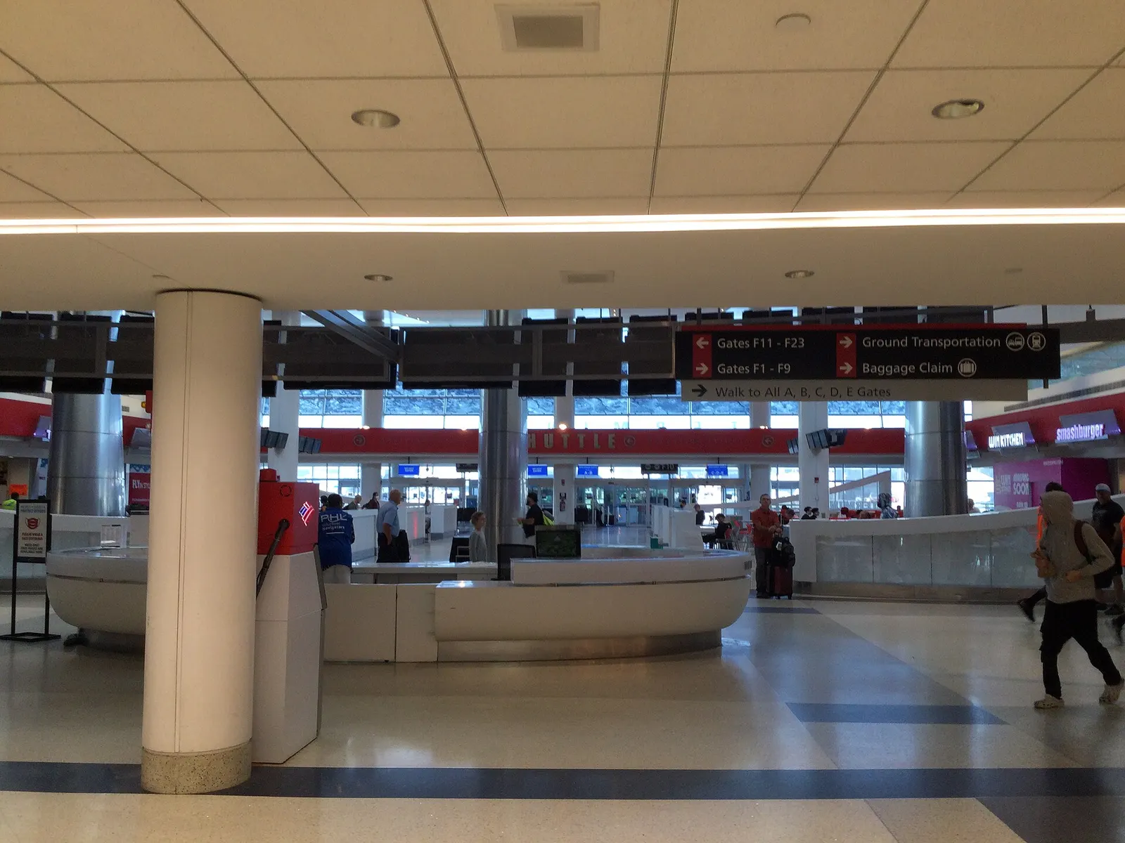 A long, bright concourse inside Terminal F with high ceilings, gate signage, seating areas, and travelers walking toward departure gates.