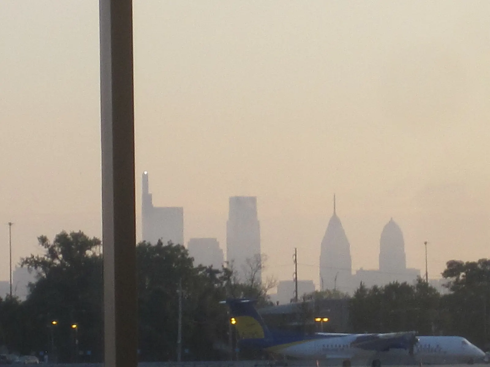 The Philadelphia downtown skyline at dawn, viewed across runways and taxiways from inside the airport.