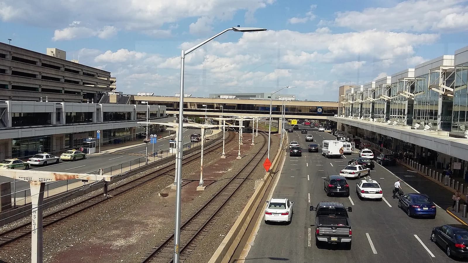 An enclosed glass footbridge connecting Terminals B and C, with the airfield and jet bridges visible through the windows.