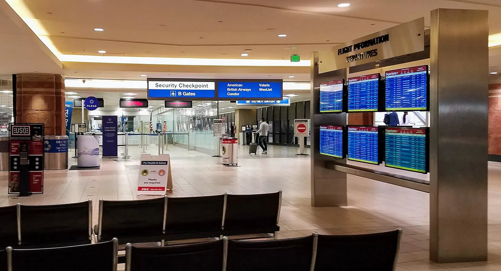 The Terminal 4 security checkpoint entrance with overhead flight information displays and directional signage.