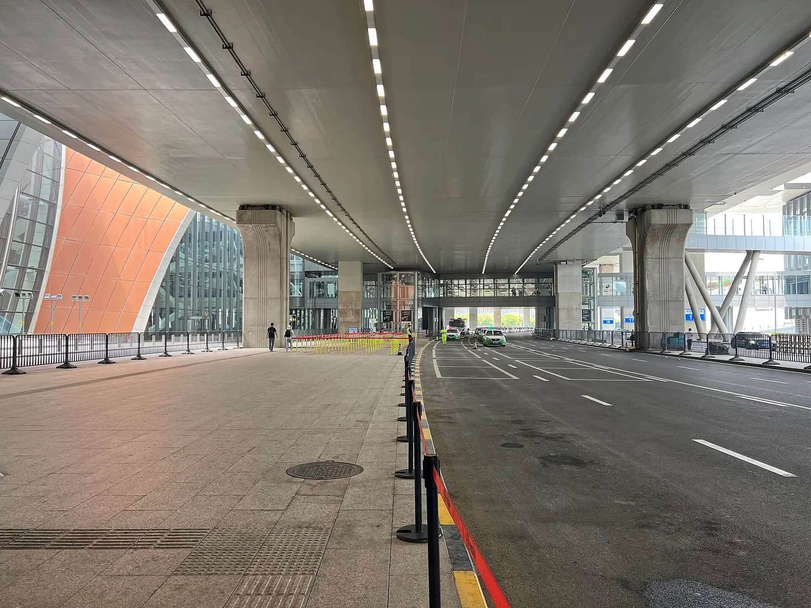 The terminal exit doors opening onto the outdoor arrivals plaza with signage for taxis, buses, and parking.