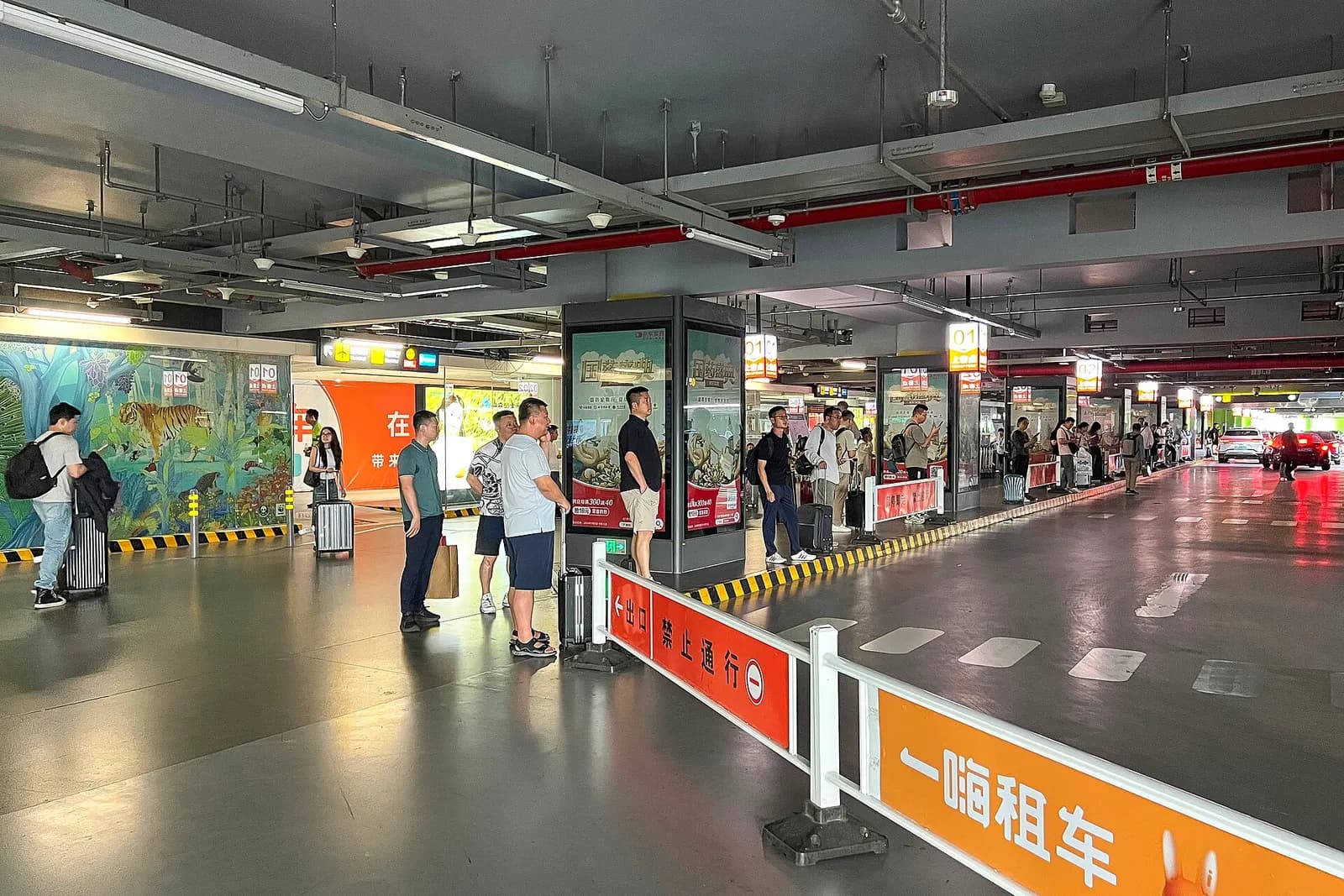 The designated ride-hailing pickup zone outside the west parking building with marked lanes and overhead signage.