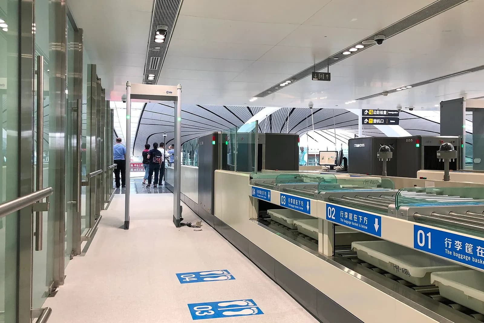 The international departures security screening area with multiple lanes, conveyor belts, and directional signage.