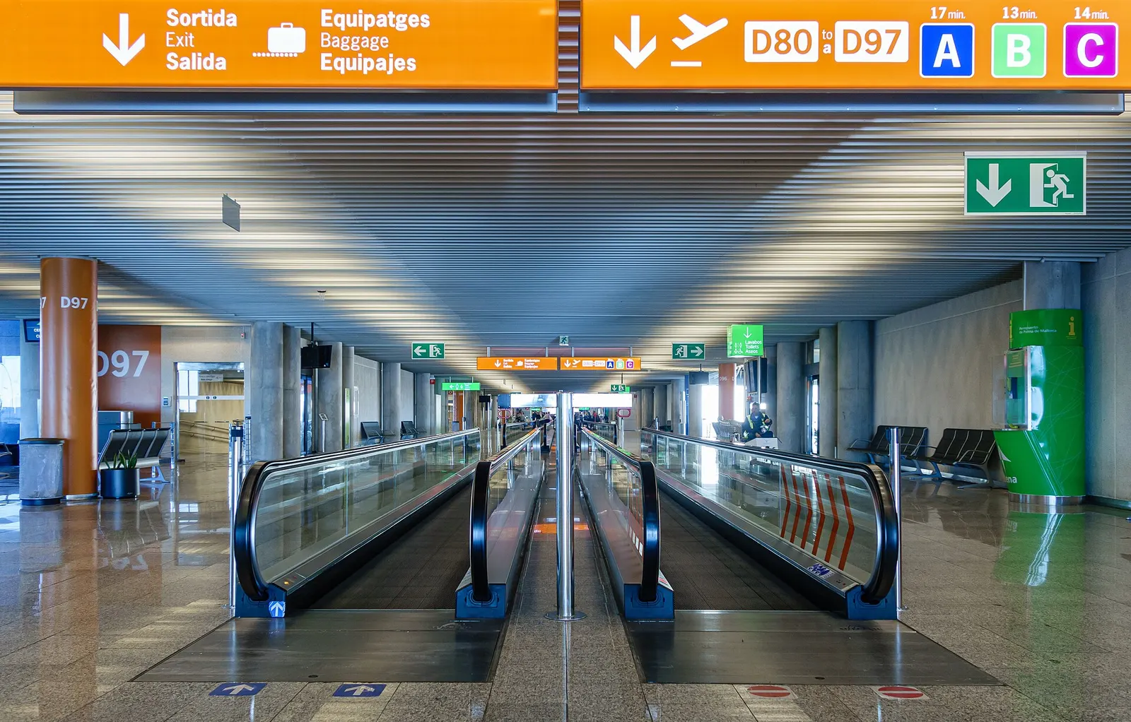 Passengers ride a moving walkway through a bright, modern corridor inside Palma de Mallorca Airport.