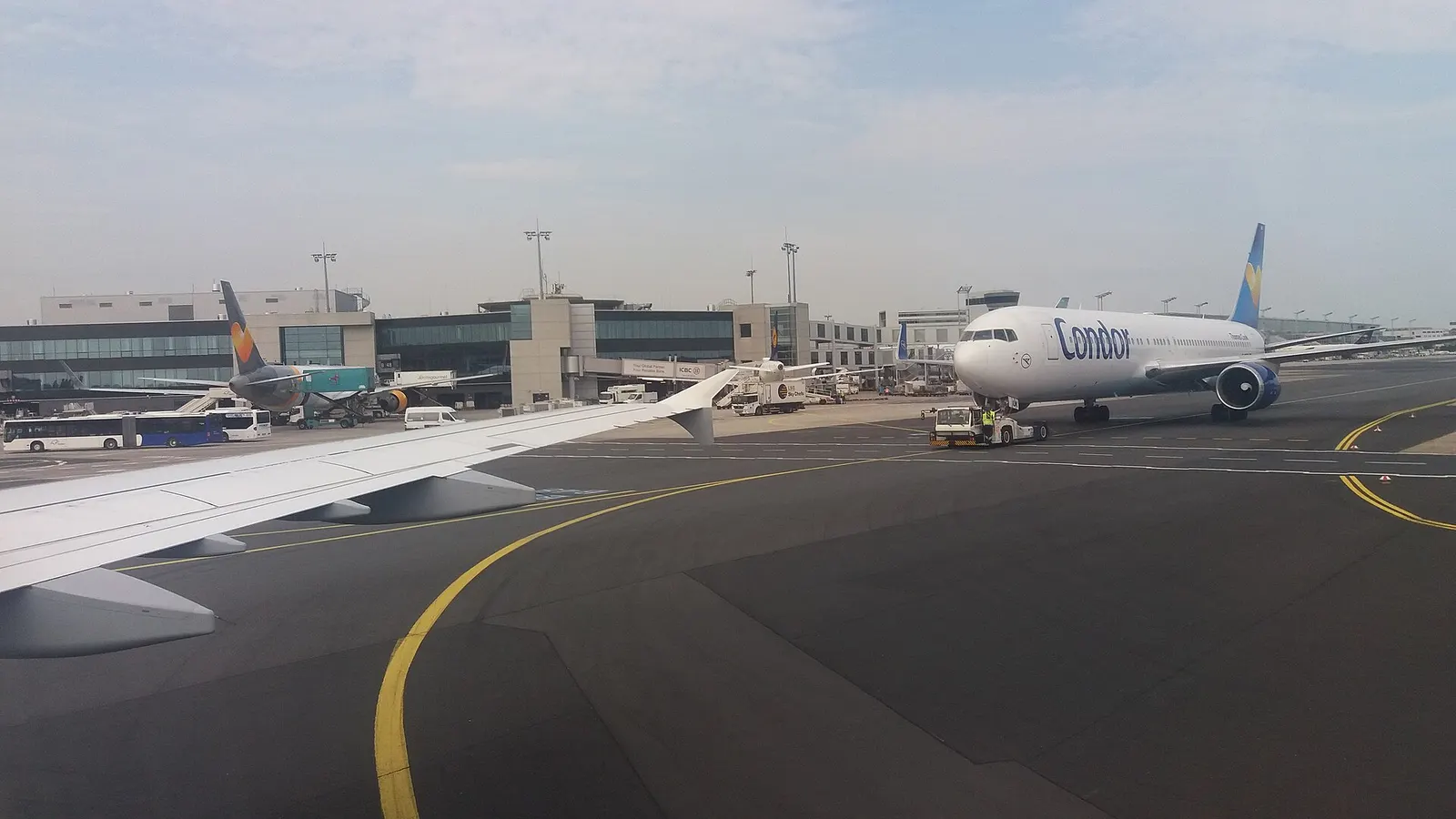 Departure gate area along Pier B at Prague Airport, with seating, gate signage, and large windows overlooking the apron.
