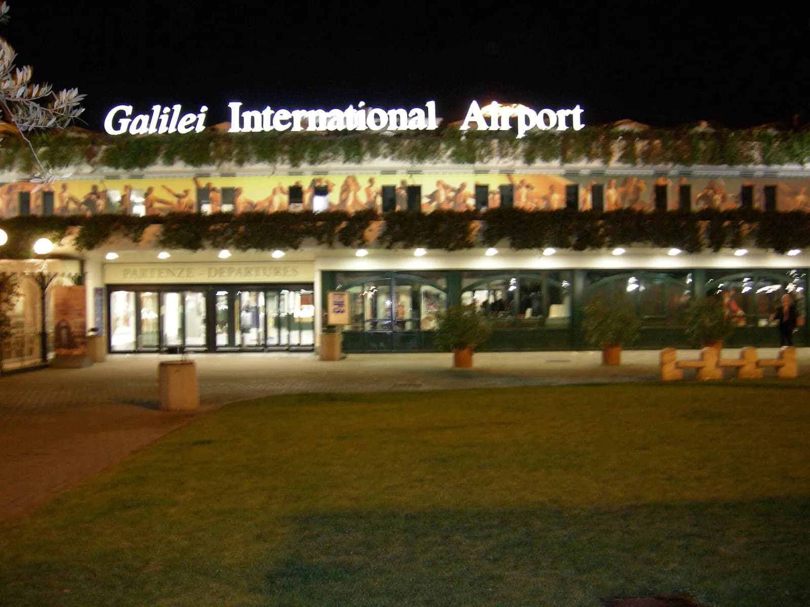 Pisa Galileo Galilei Airport terminal illuminated at night around dawn.