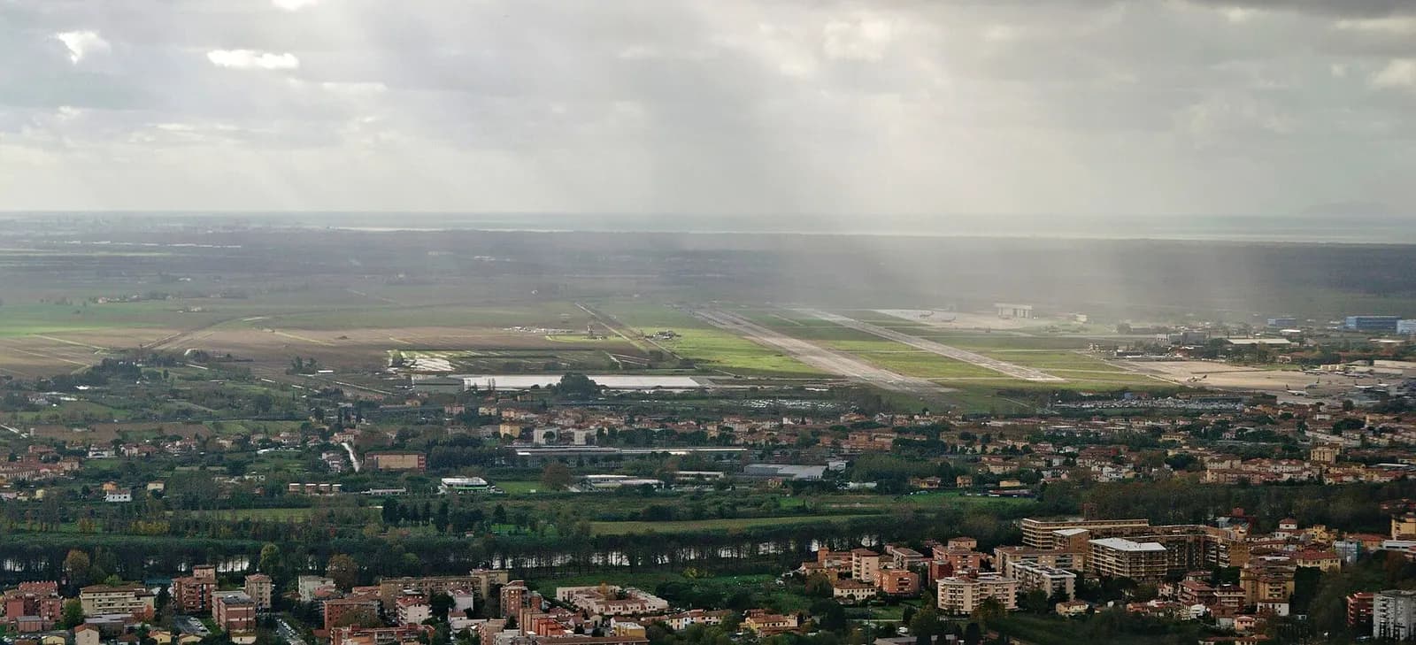 Aerial view of Pisa San Giusto Airport looking southwest with the coastline beyond.