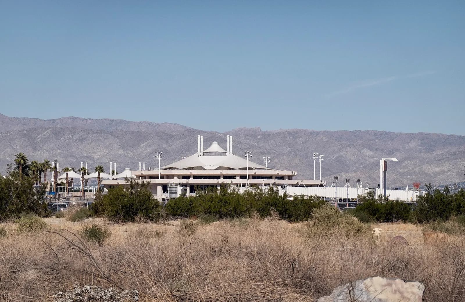 Daytime view of the Palm Springs International Airport terminal and curb from the parking side.