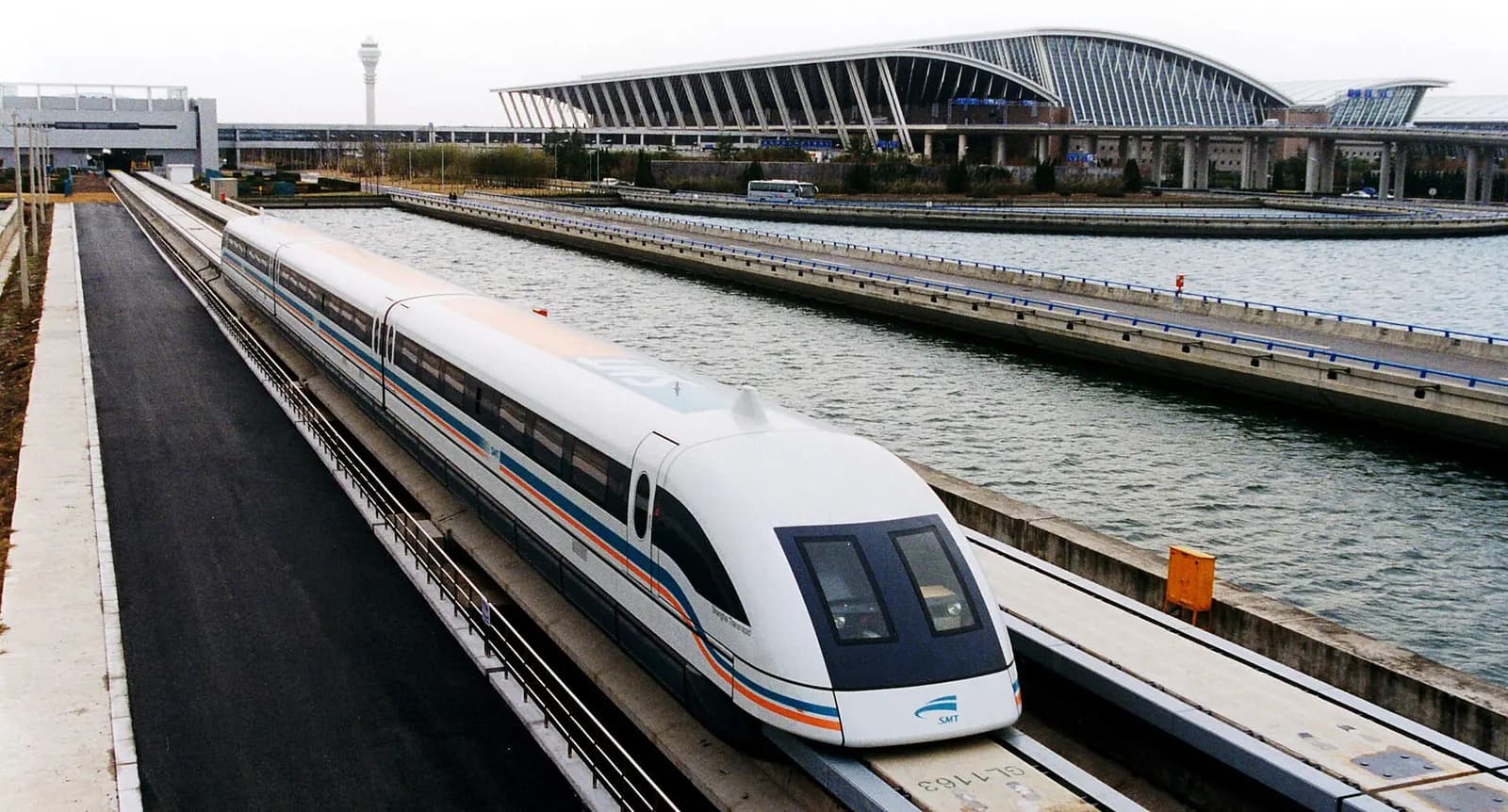 A white Shanghai maglev train emerging from the Pudong International Airport station.