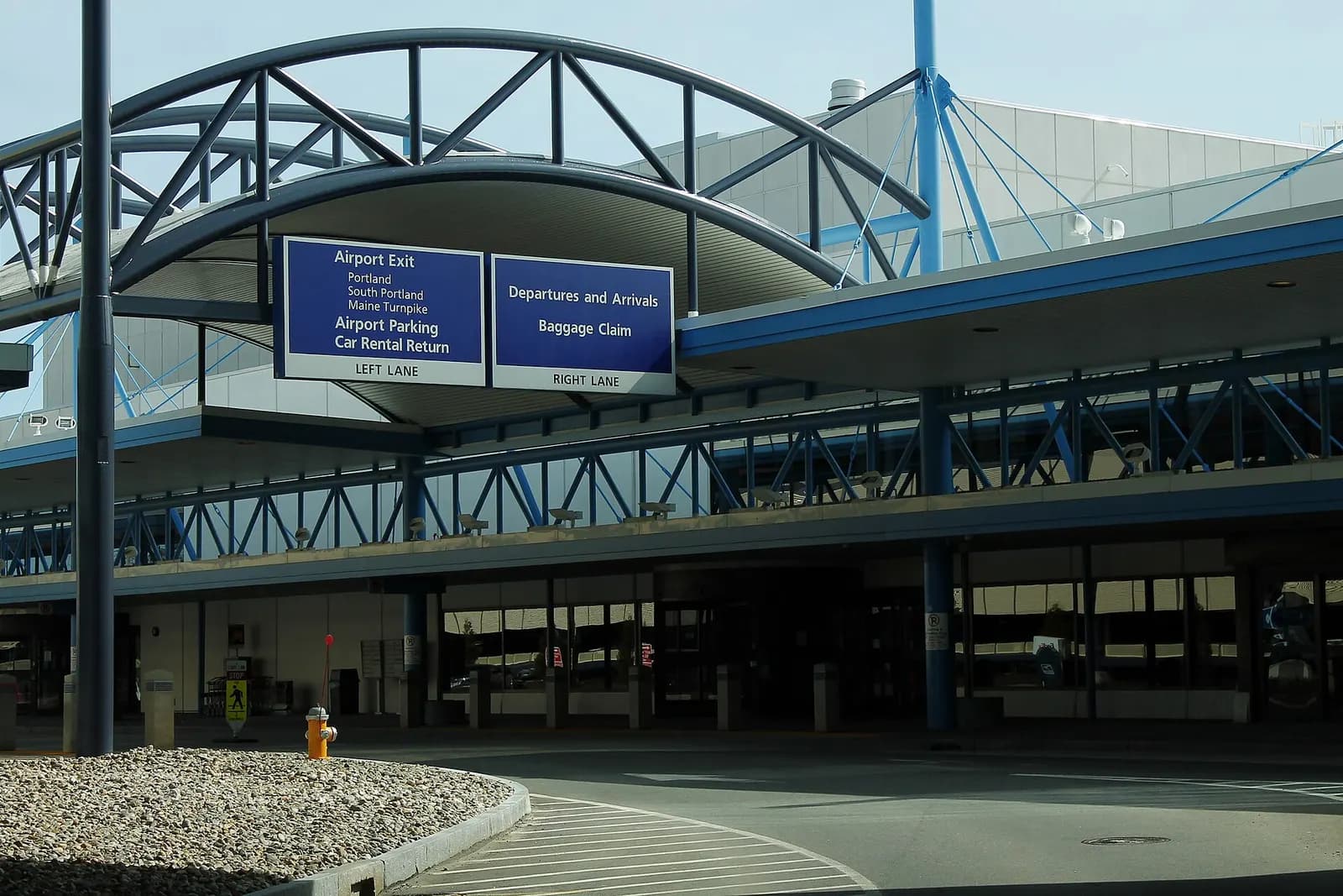 Departures and arrivals curb at Portland International Jetport with the terminal canopy and garage beyond.