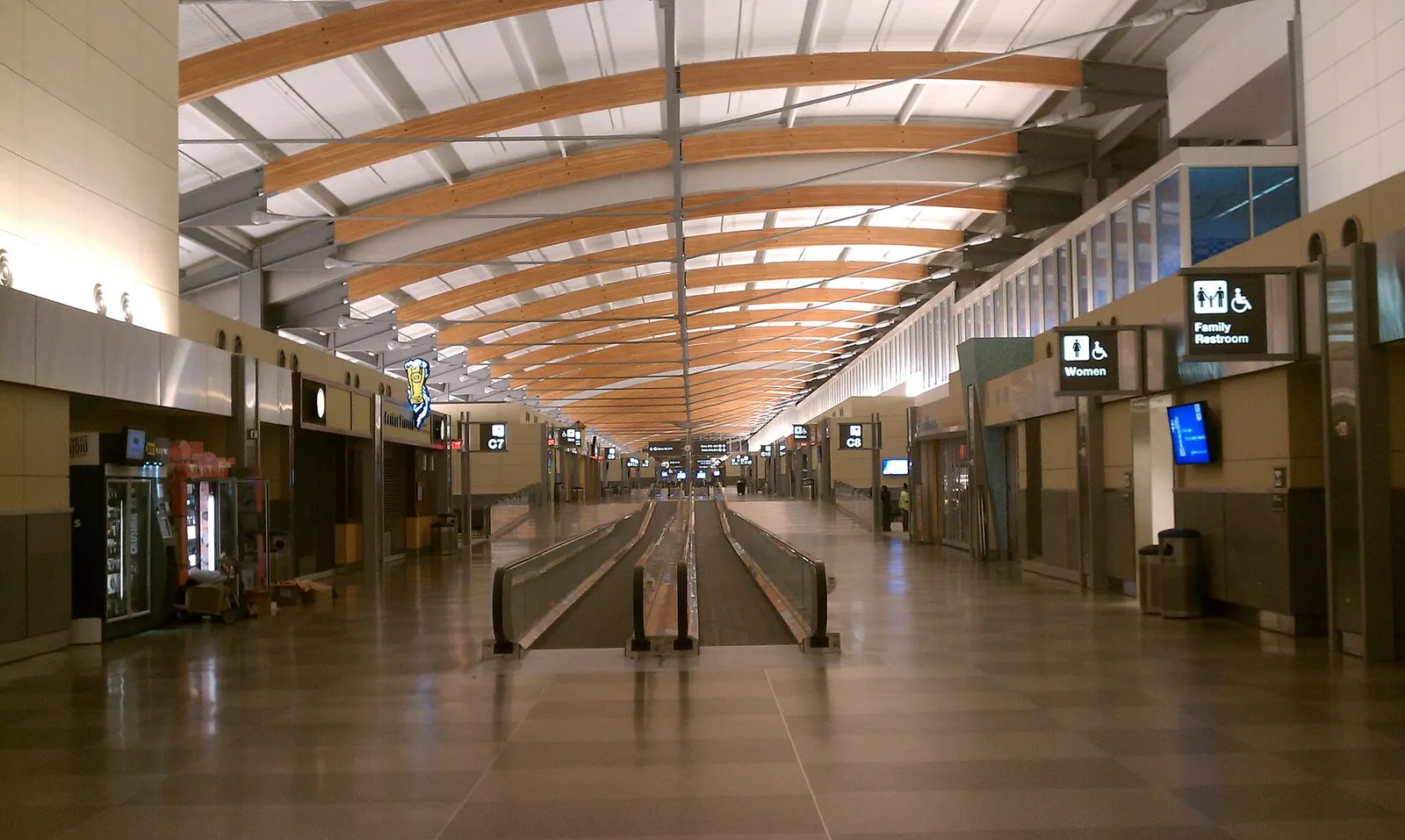The landside interior of an RDU terminal with check-in counters, signage, travelers, and open public space under the ceiling structure.