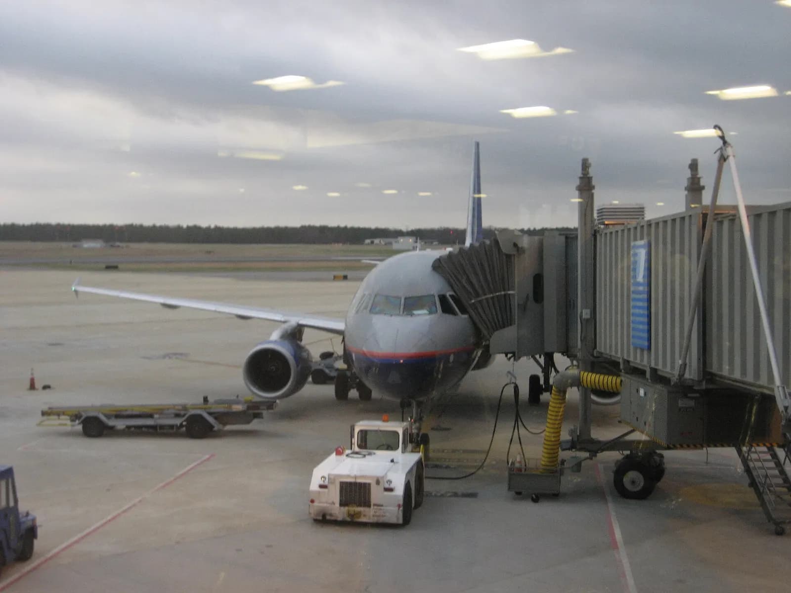 United Airbus A320 parked at a Richmond International Airport jet bridge with a tug in the foreground.