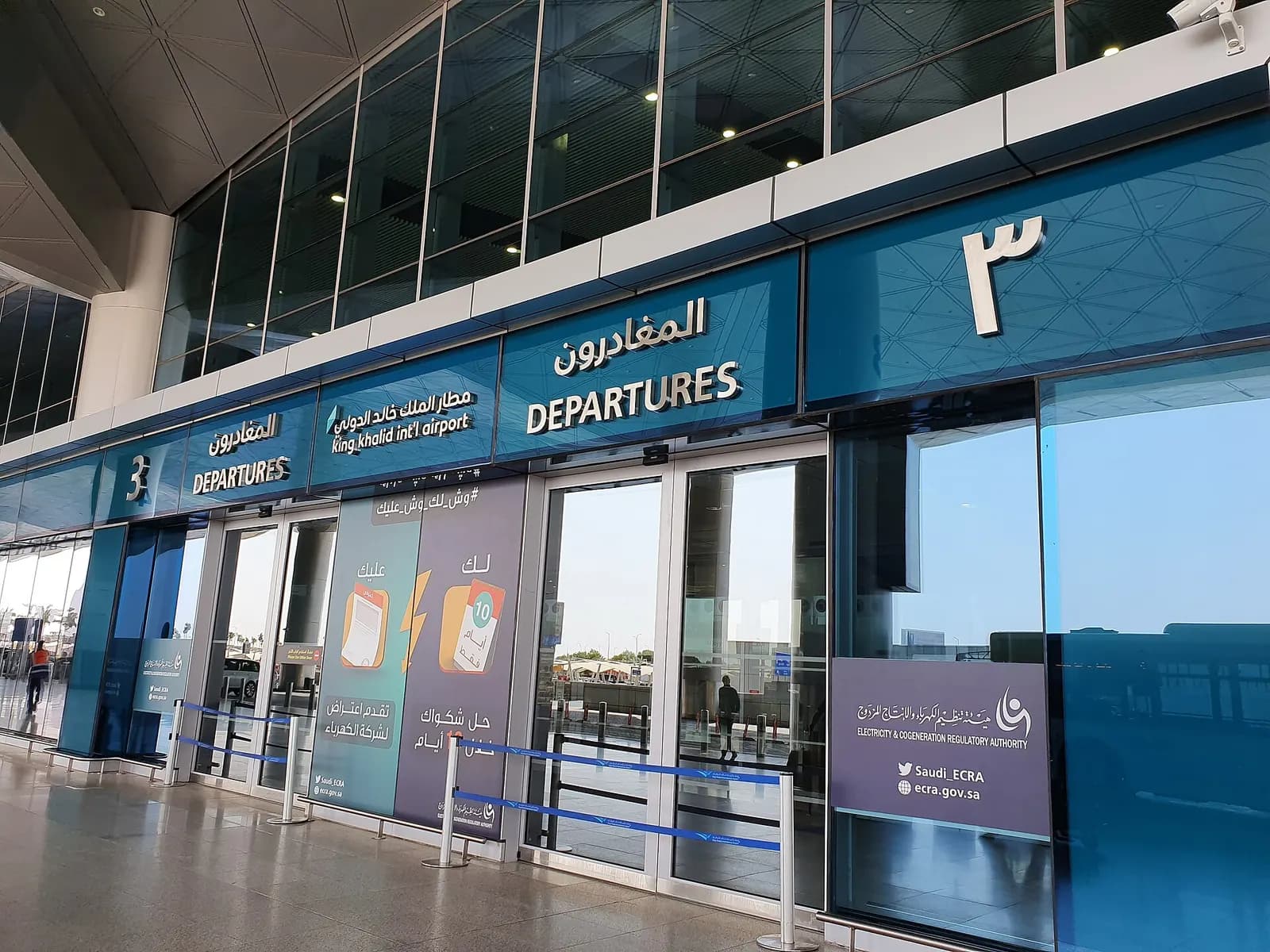 Inside the domestic departures area with gate seating, overhead signage, and passengers waiting at King Khalid International Airport.