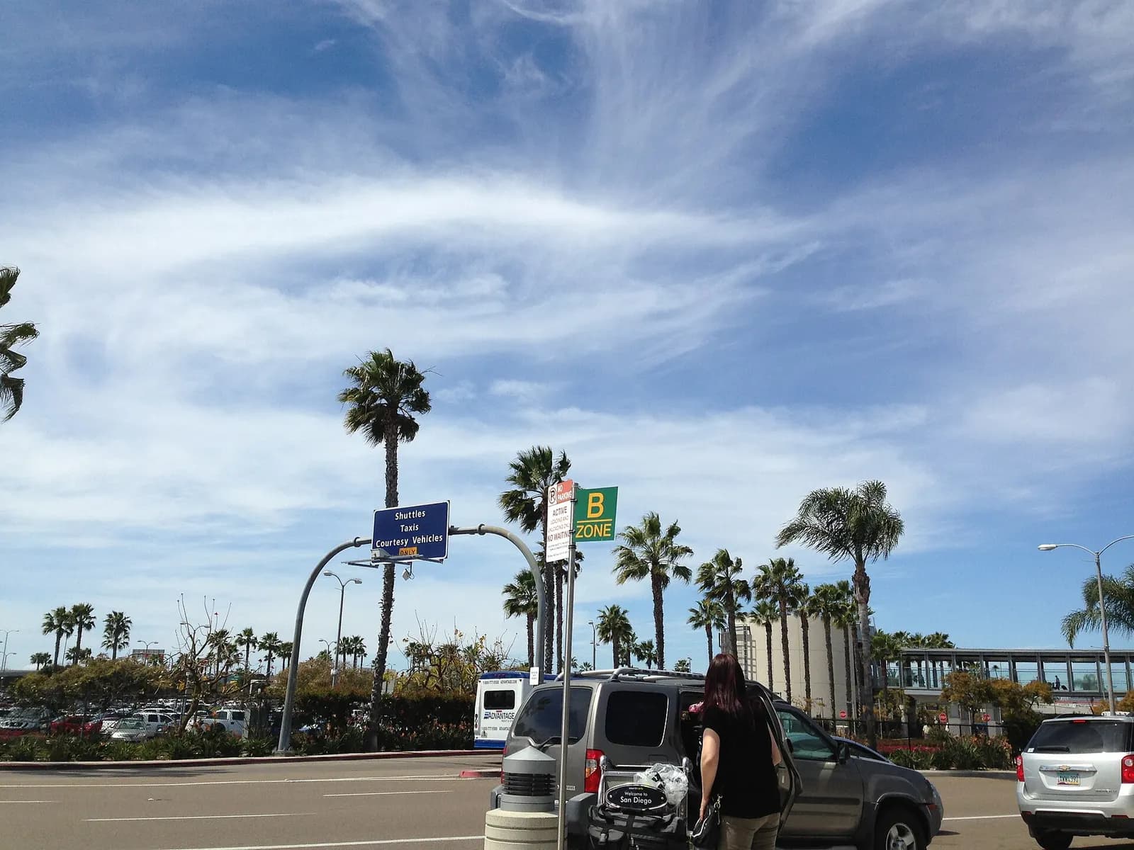 The outdoor arrivals level at San Diego International Airport with covered walkways, taxis, and passenger pickup lanes.
