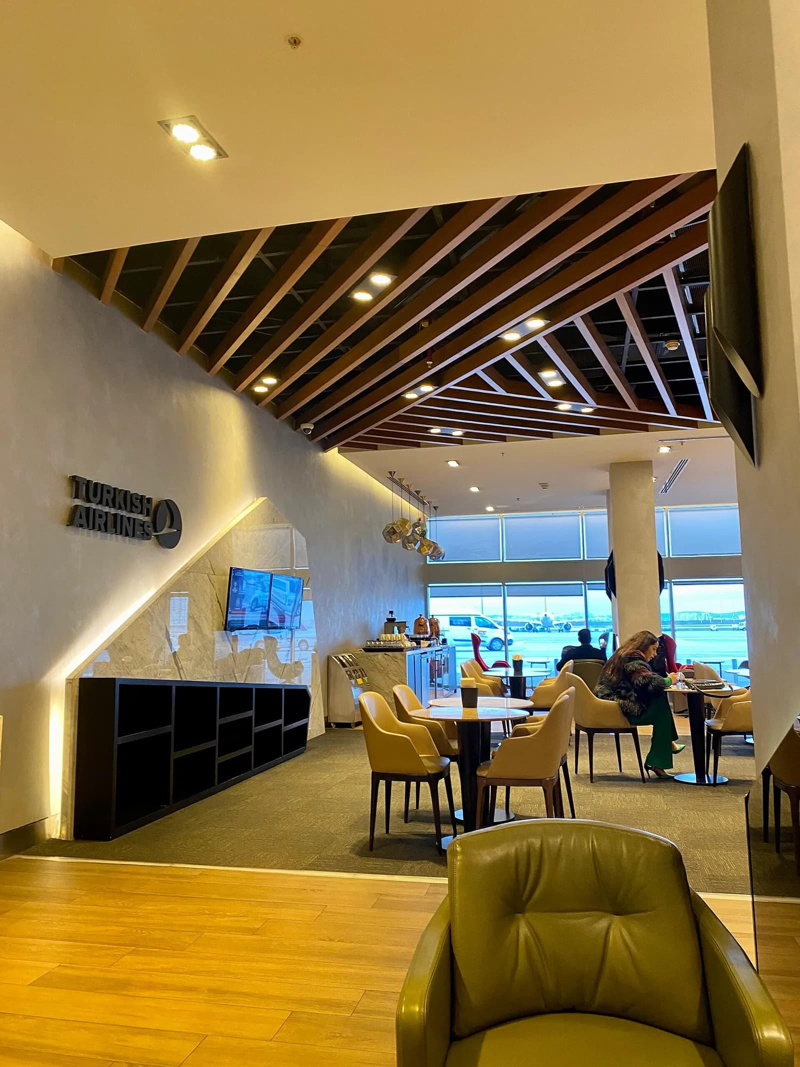 The Turkish Airlines lounge at Sabiha Gökçen Airport with upholstered seating, tables, and a food service area.