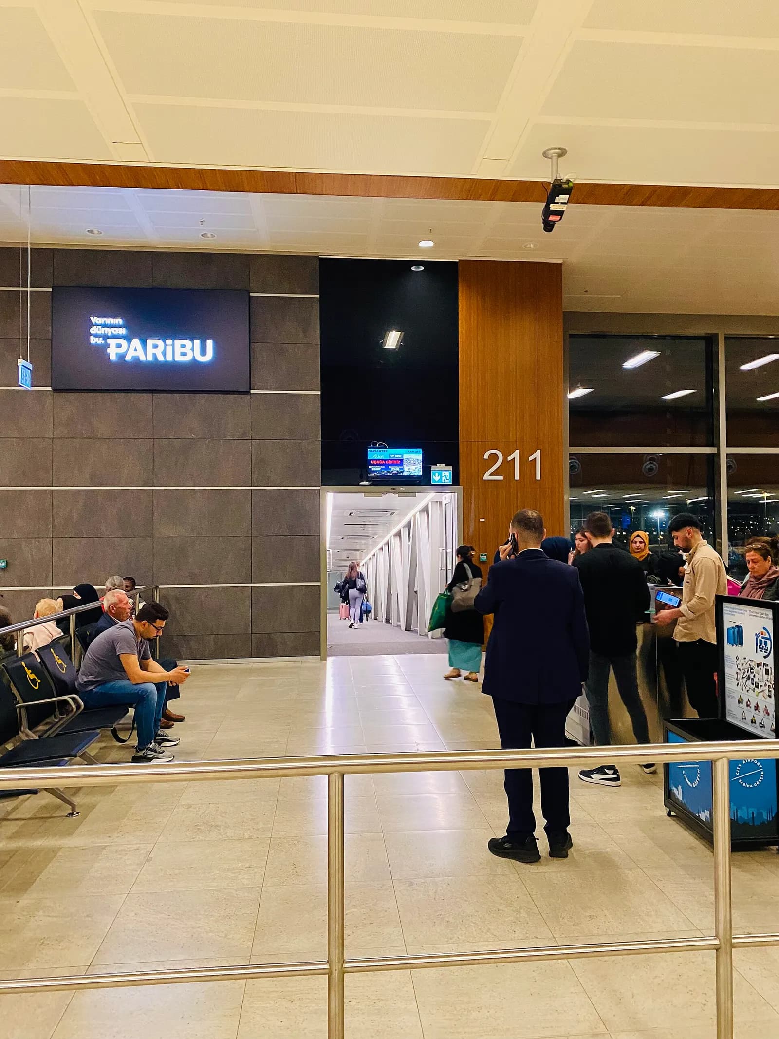Domestic departure gate 211 with passenger seating, flight information screens, and boarding-area signage.