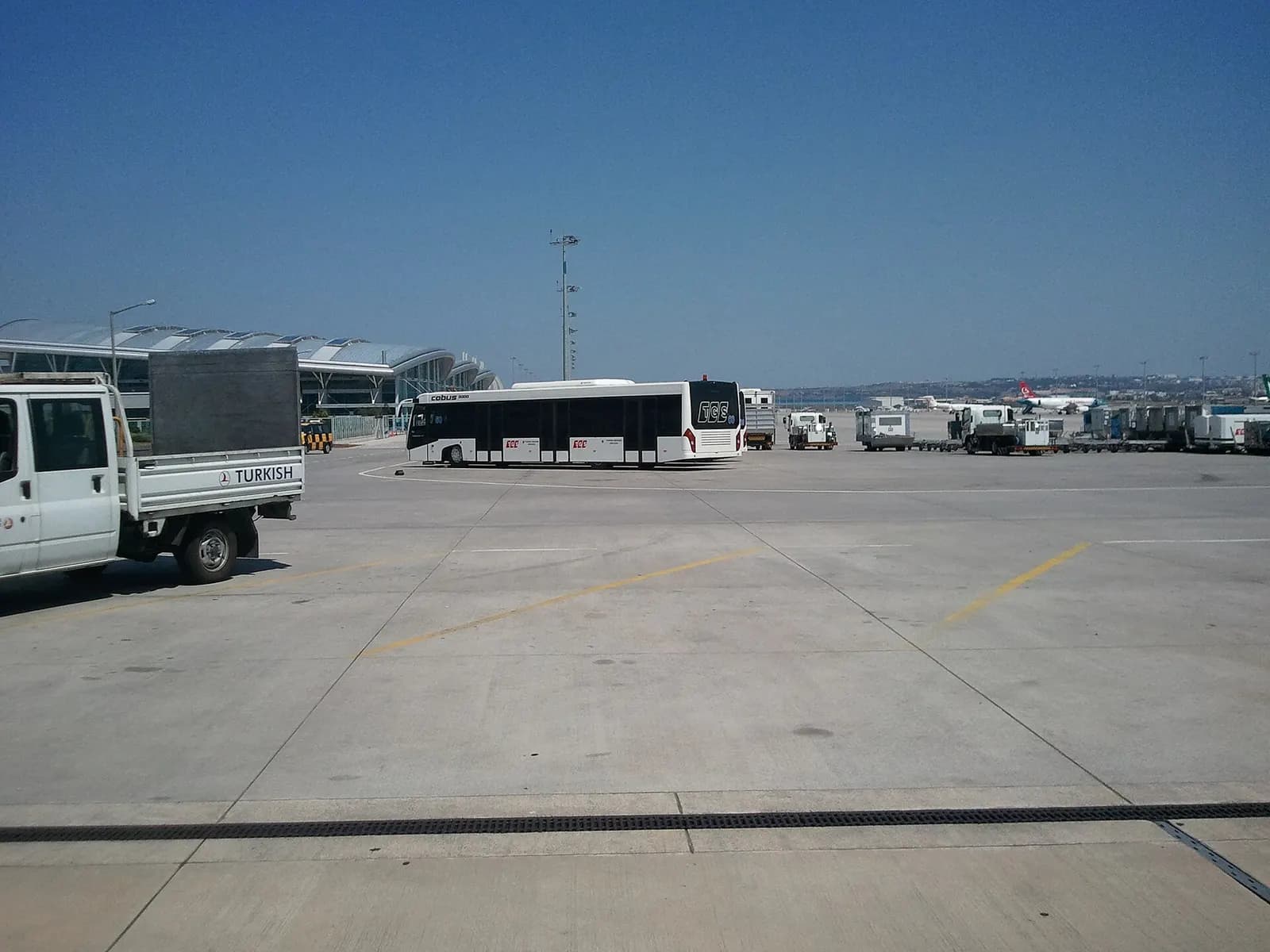 A wide view across the Sabiha Gökçen apron showing the terminal facade and several aircraft at the gates.