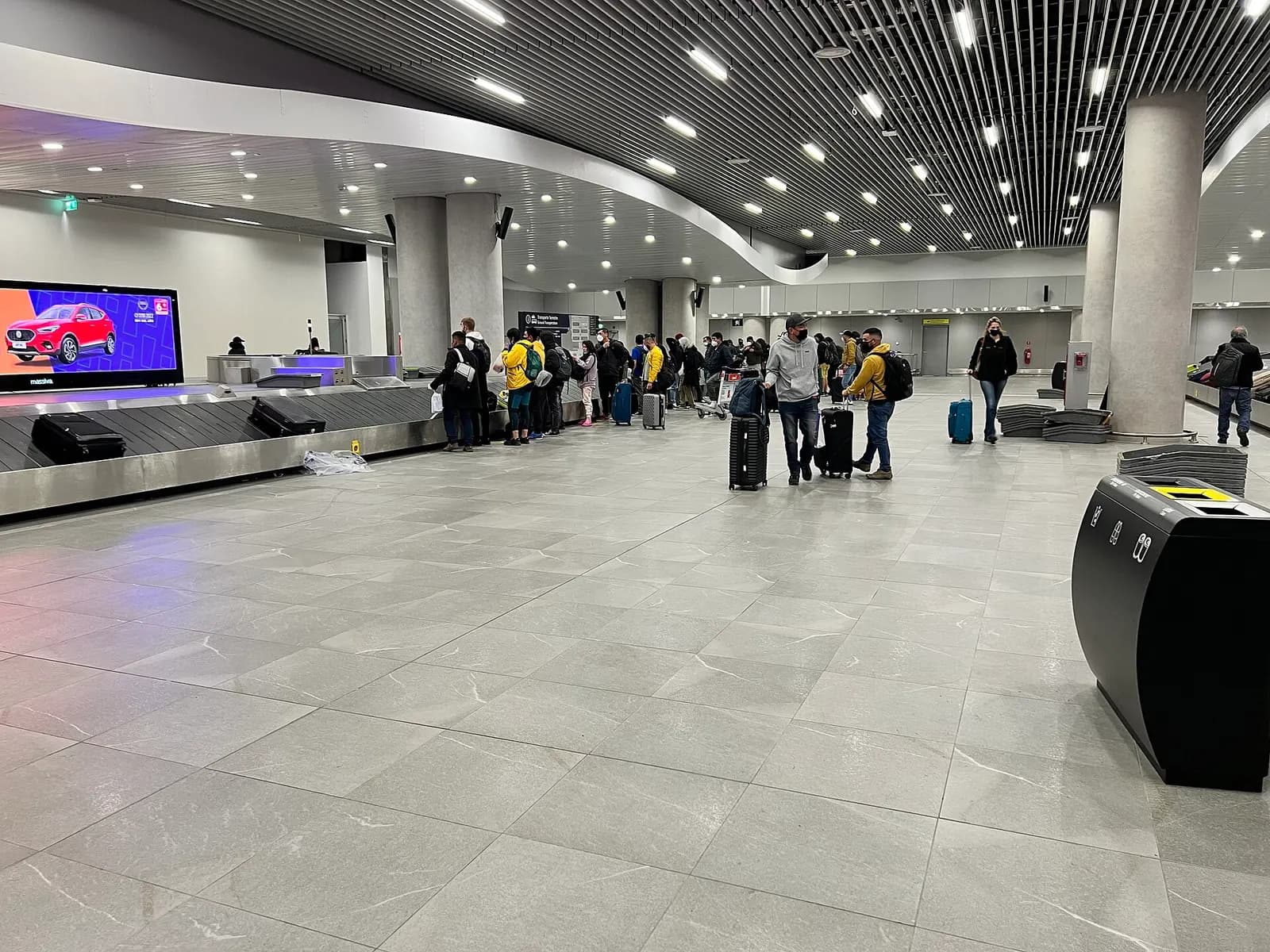 Baggage carousels and arriving travelers in the international terminal baggage claim area.