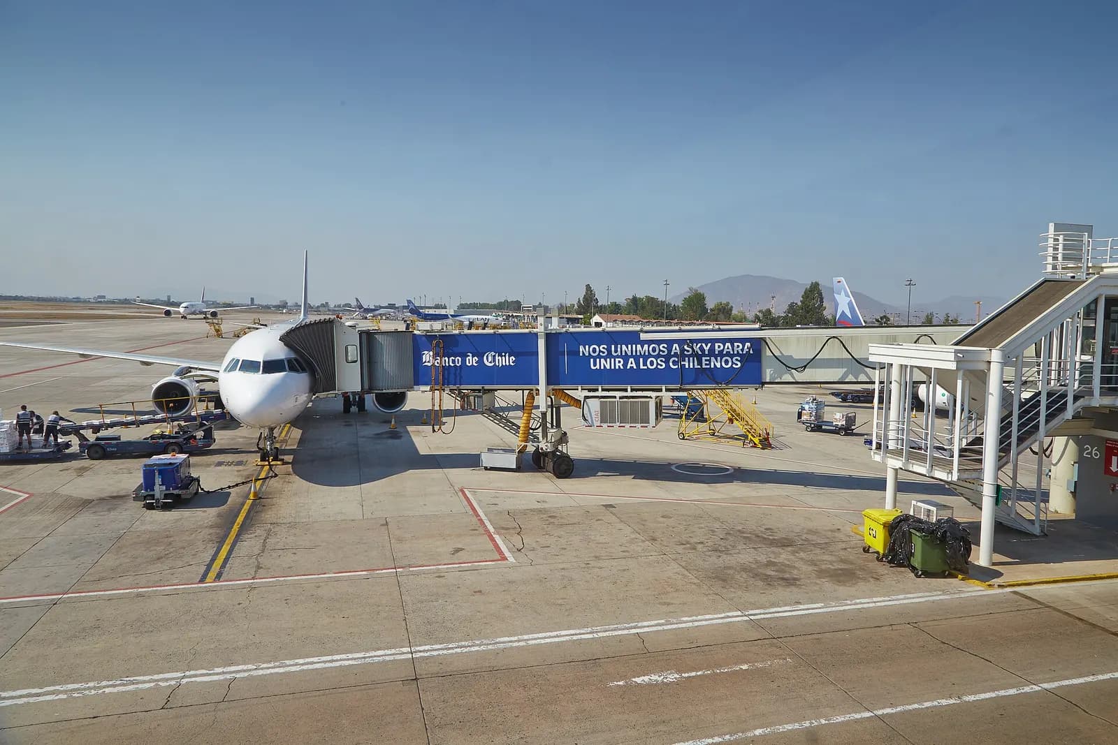 A wide aerial-style view of the airport tarmac showing runways, ramps, terminal structures, and distant aircraft.