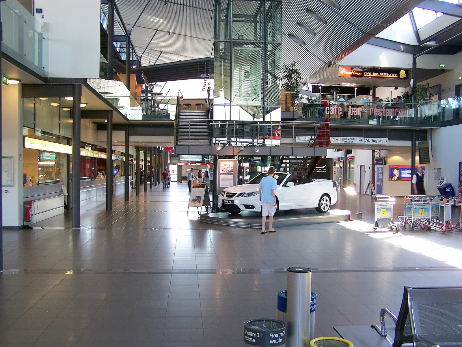 Saarbrücken Airport passenger terminal exterior with glass facade and approach road.