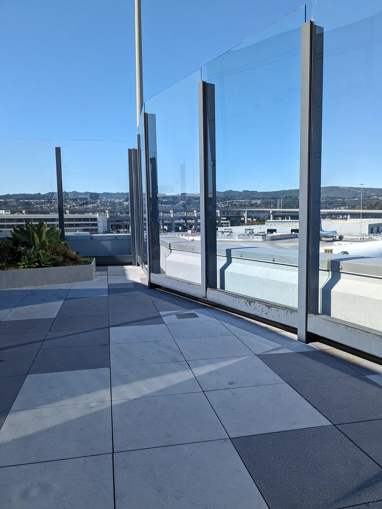 An outdoor terrace with seating and planters in the International Terminal, offering open-air space inside the secure area.