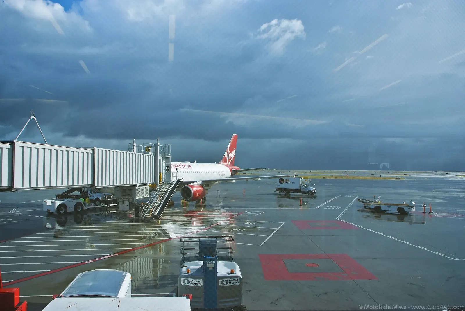 Rain streaks the windows of Terminal 2 at SFO, reflecting warm interior lights across the gate-area seating.