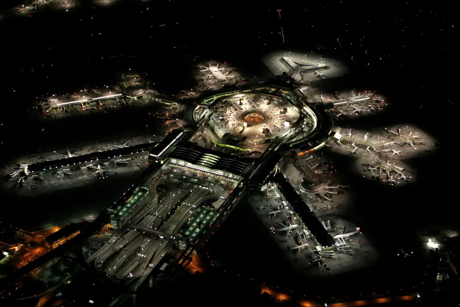 San Francisco International Airport's illuminated terminals and airfield glow against a deep blue night sky.