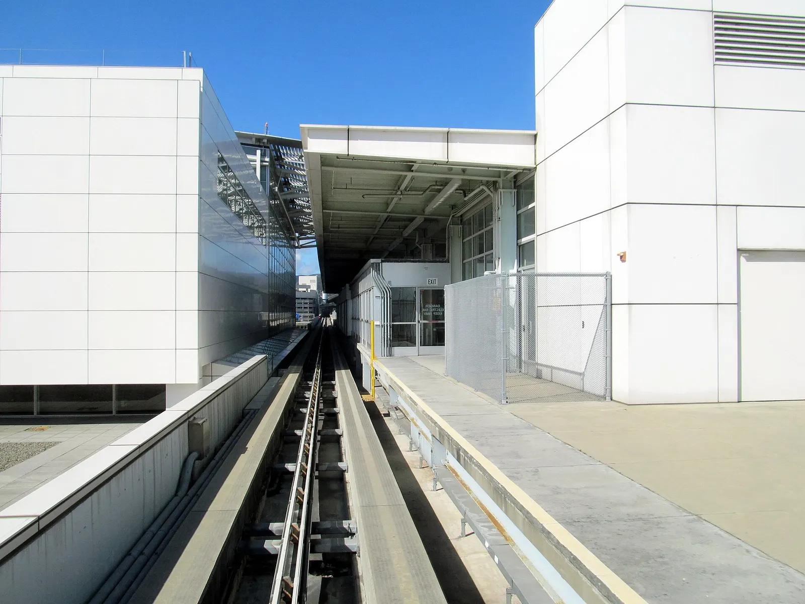 The SFO AirTrain platform at International Terminal G station, with the automated people-mover train and terminal building visible.