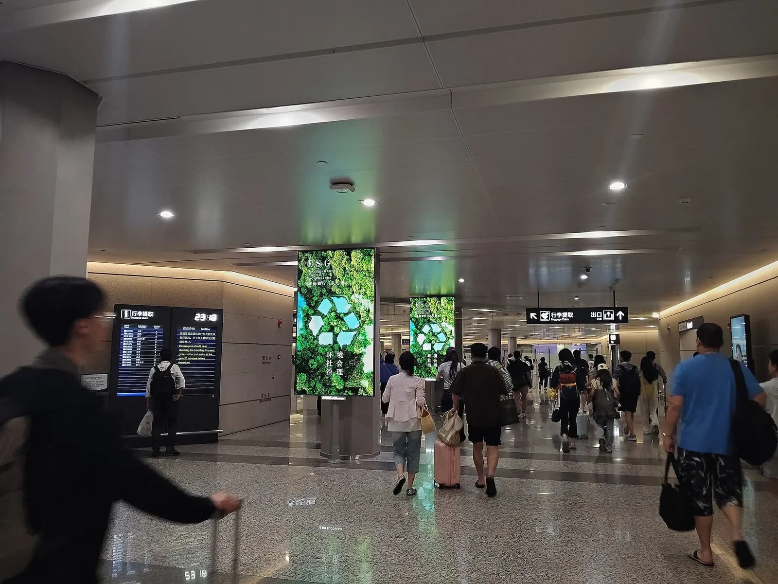 The domestic arrivals level in Terminal 1 has baggage claim carousels, wayfinding signs, and passengers walking toward the terminal exits.