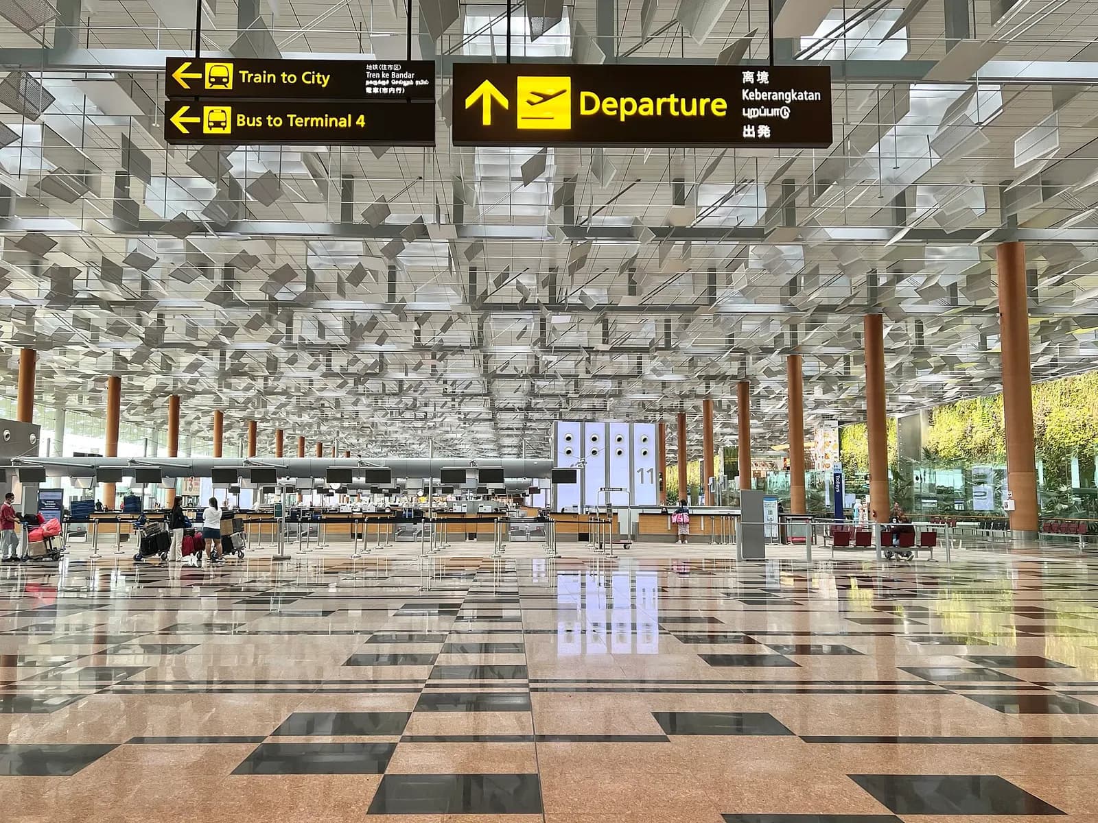 Travelers walk through a spacious, brightly lit Changi Airport concourse with high ceilings, shops, and directional signage.