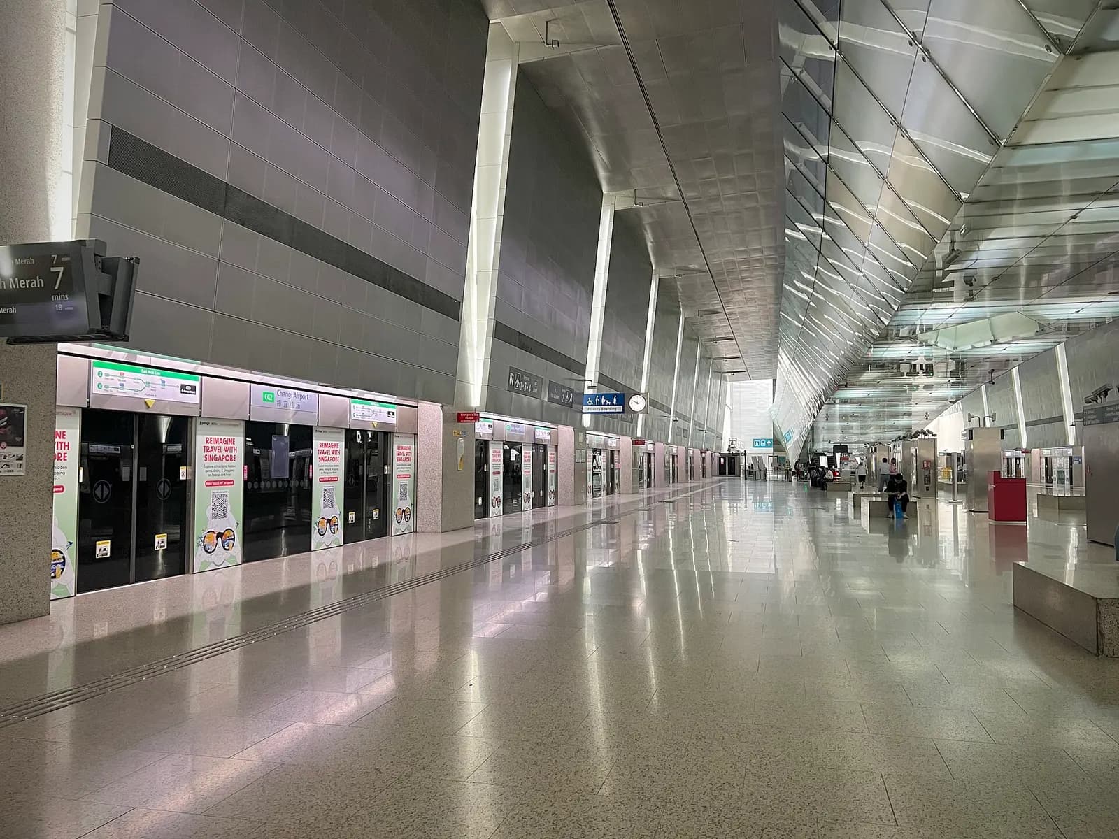 The Changi Airport MRT station platform and concourse with trains, ticket gates, and signs for the downtown East West Line.