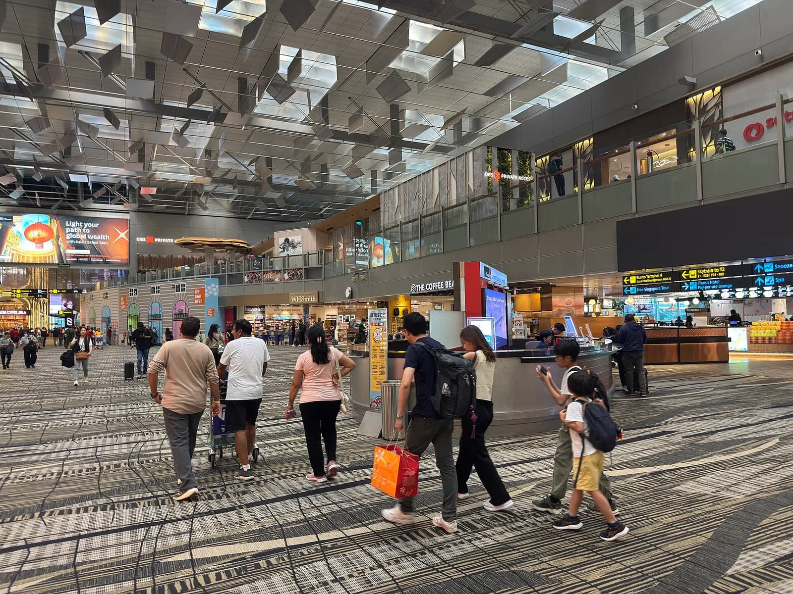 The airside departure hall in Terminal 3 shows gate seating areas, flight information displays, and large windows overlooking the tarmac.