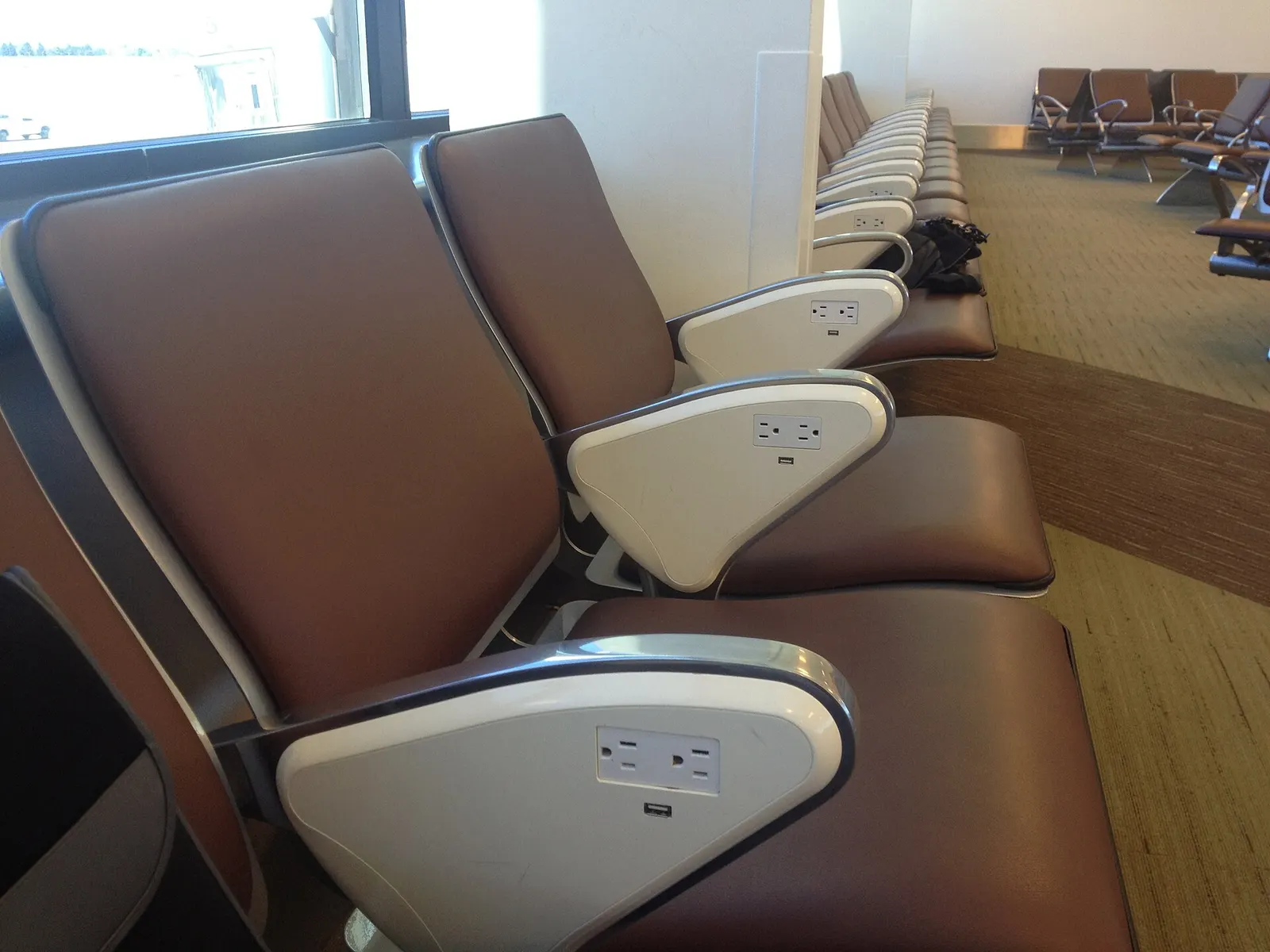 Airport seats in Norman Y. Mineta San José International Airport Terminals, that have sockets in each armrest.