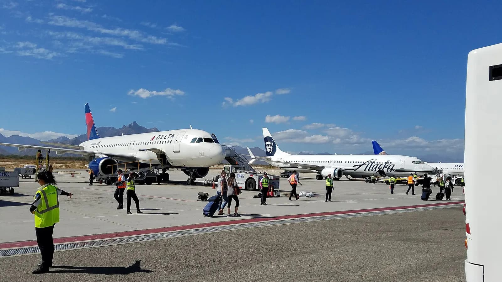 Passengers boarding various flights at Los Cabos International Airport while walking on the ramp.