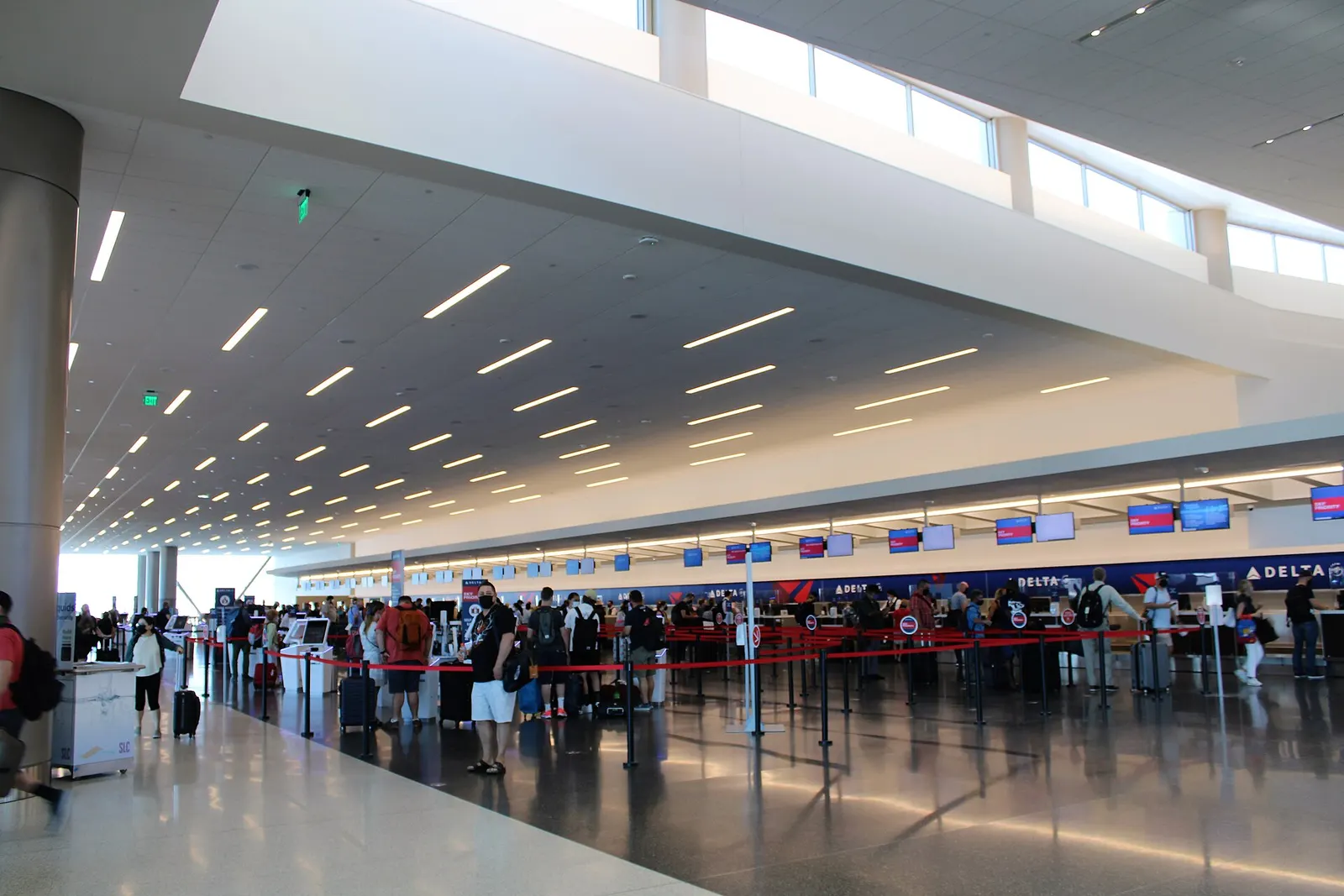 Wide interior view of the Salt Lake City International Airport main terminal with travelers, shops, and soaring architectural ceilings.